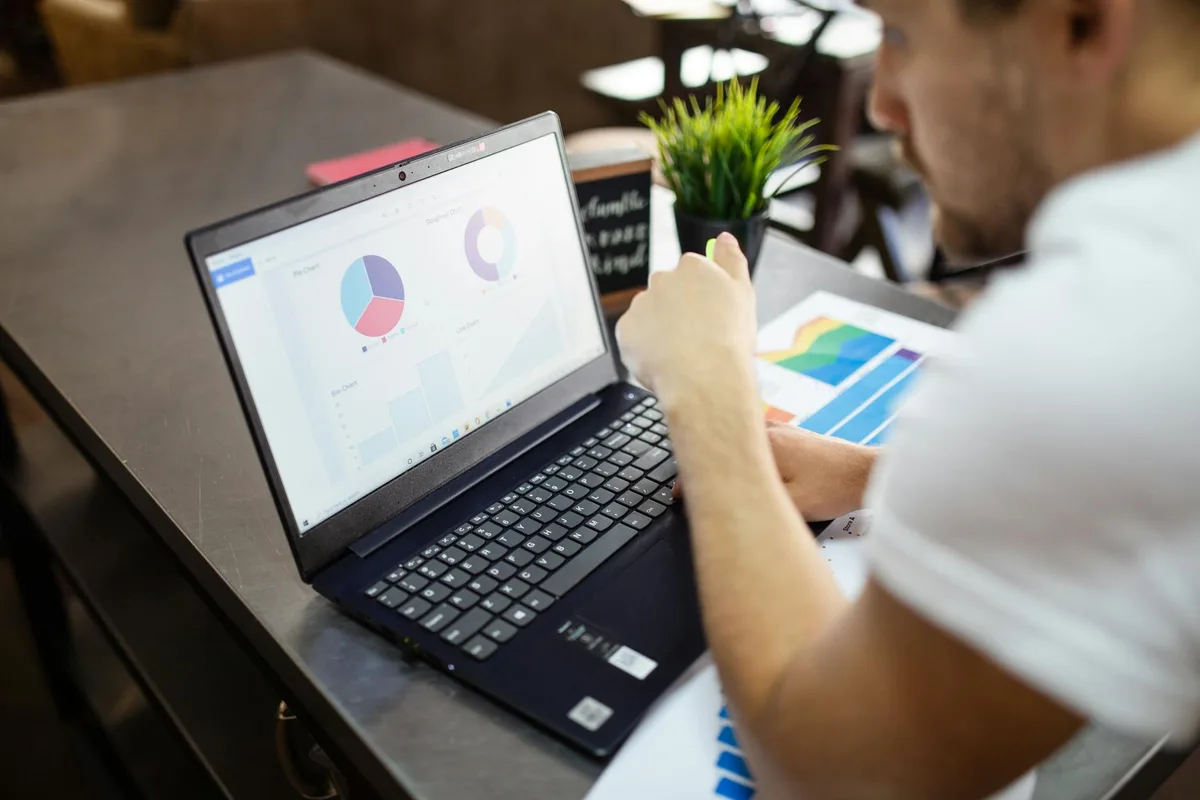 Filipino ecommerce seller reviewing email campaign analytics on a laptop with packaged products and a smartphone on the desk