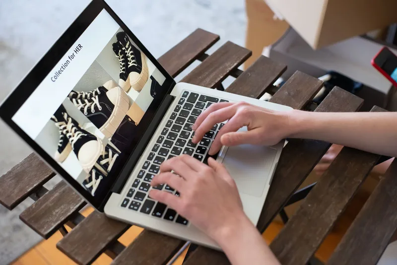 Person browsing online fashion store product collection on a laptop, representing Shopify product page experience for UAE ecommerce shoppers